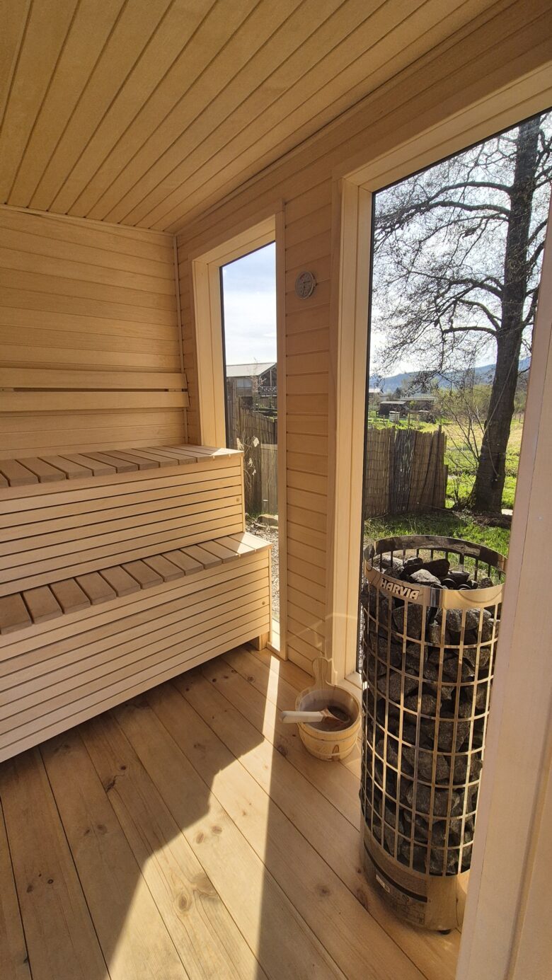 Sauna interior with wooden benches and stone heater at Bohemian Homes.